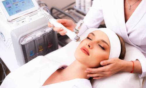 Clinic of aesthetic cosmetology. Facial exfoliation procedure. The patient does a hydro-peeling at the cosmetologist. Facial skin rejuvenation concept.